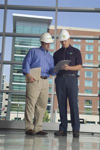 2 men in hard hat assessing damage