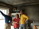 Three people standing in a burned down room